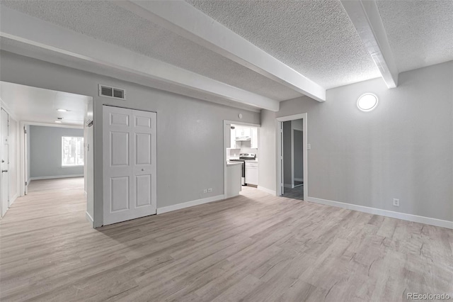 empty room with a textured ceiling, light hardwood / wood-style flooring, and beam ceiling