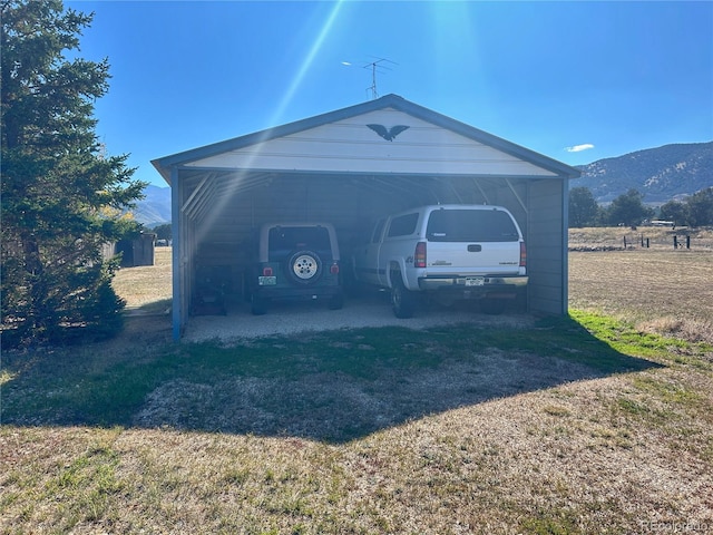 garage featuring a carport, a lawn, and a mountain view