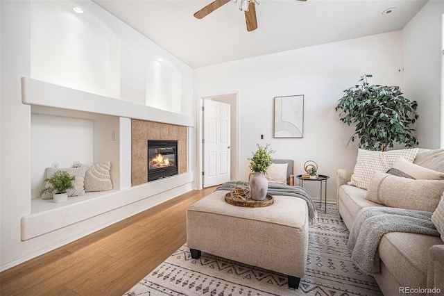 living room with ceiling fan, hardwood / wood-style floors, and a tiled fireplace