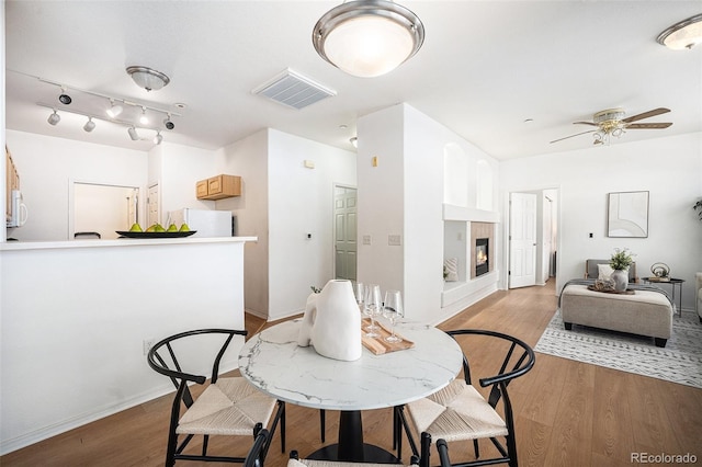 dining area featuring ceiling fan, light hardwood / wood-style floors, and a tiled fireplace