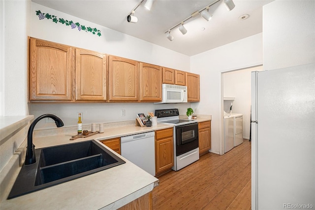 kitchen featuring sink, white appliances, light hardwood / wood-style floors, and separate washer and dryer