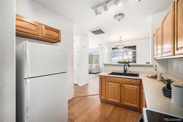 kitchen featuring hanging light fixtures, sink, range, light hardwood / wood-style floors, and white fridge