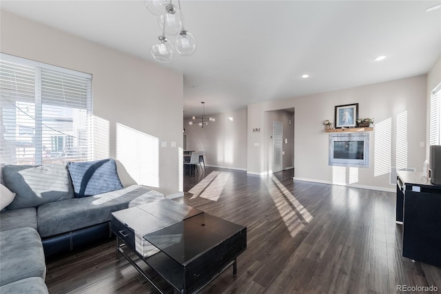 living room with dark wood-type flooring, an inviting chandelier, recessed lighting, and baseboards