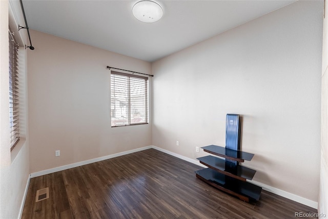 unfurnished bedroom featuring dark wood-style floors, visible vents, and baseboards