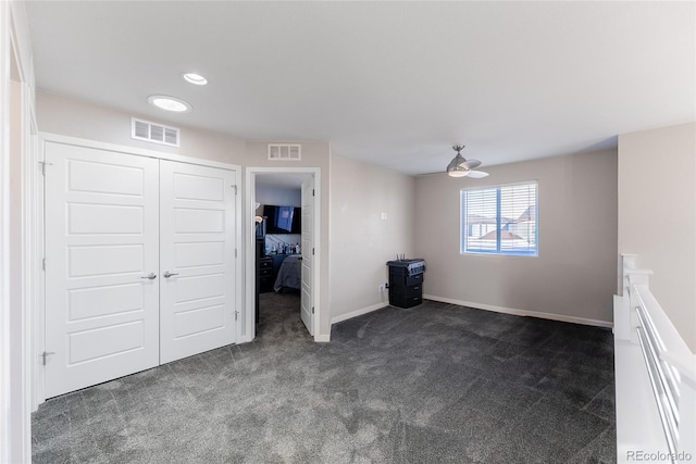 unfurnished room featuring visible vents, dark carpet, baseboards, and ceiling fan