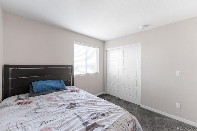 bedroom with baseboards, dark colored carpet, and a closet