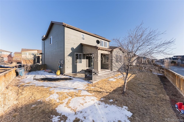 snow covered house featuring fence and a patio