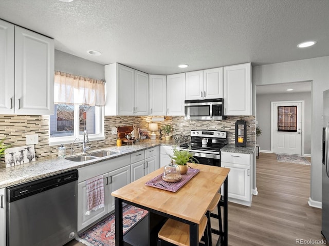 kitchen featuring white cabinetry, sink, stainless steel appliances, and light stone countertops