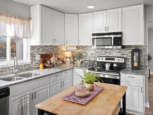 kitchen with light stone counters, sink, stainless steel appliances, and white cabinets