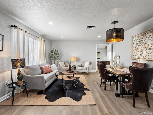 living room with a textured ceiling and light wood-type flooring