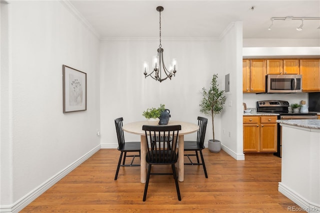 dining space with a chandelier, light wood finished floors, baseboards, and crown molding