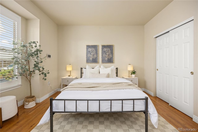 bedroom featuring wood finished floors, baseboards, and a closet