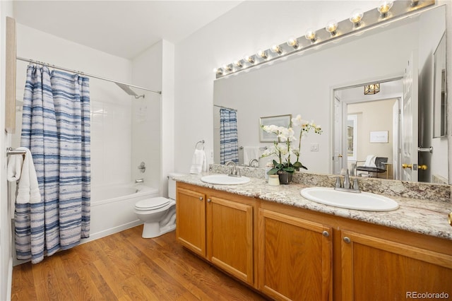 full bath with wood finished floors, double vanity, shower / bath combination with curtain, and toilet
