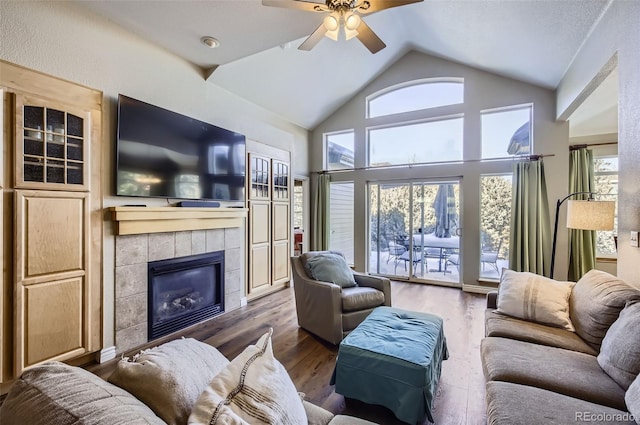 104 Noland Ct, Lyons, CO 80540 - living room featuring vaulted ceiling, ceiling fan, a tiled fireplace, and wood finished floors