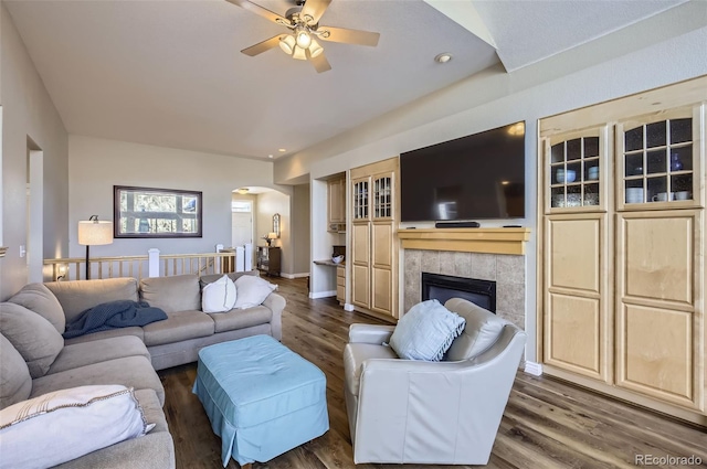 104 Noland Ct, Lyons, CO 80540 - living area with arched walkways, a ceiling fan, dark wood-style floors, and a tiled fireplace