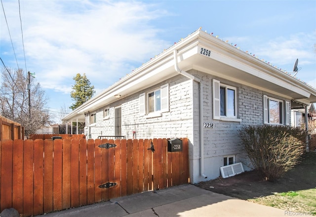 view of home's exterior featuring brick siding, a gate, and fence