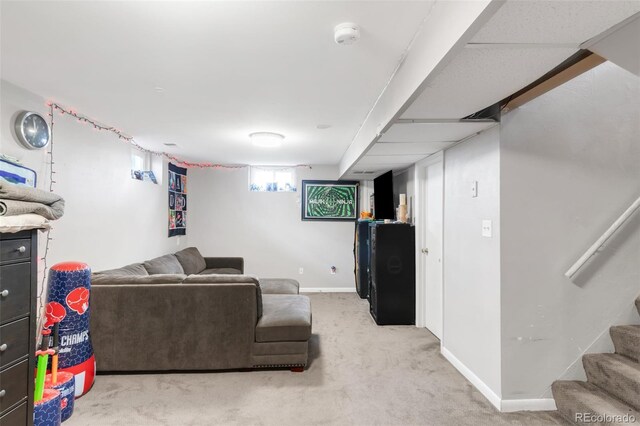 living area with baseboards, stairs, and light colored carpet