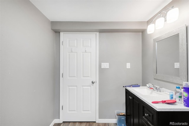 bathroom with wood finished floors, baseboards, and vanity