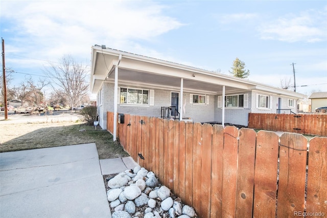 view of front of property with brick siding, a patio area, and fence