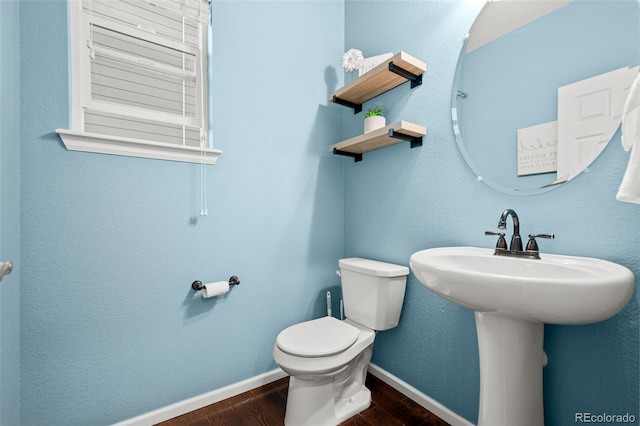 half bath featuring baseboards, wood finished floors, and toilet