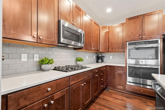 kitchen featuring light countertops, appliances with stainless steel finishes, dark wood-style floors, and decorative backsplash