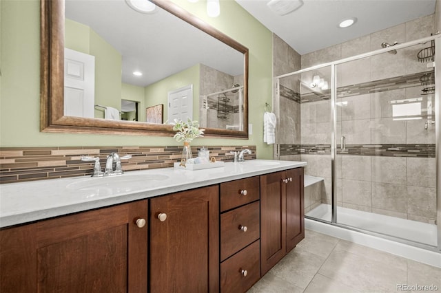bathroom with tile patterned flooring, a stall shower, decorative backsplash, and a sink