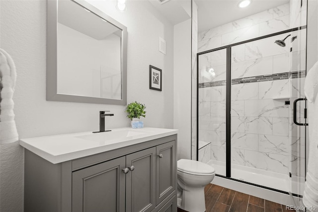 bathroom with vanity, wood finished floors, a shower stall, and toilet