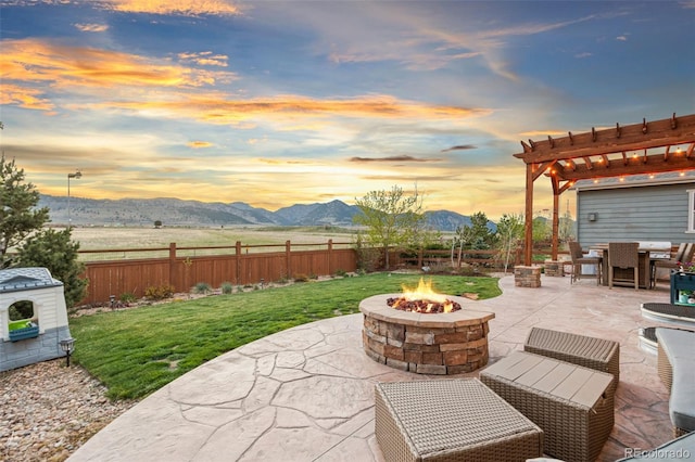 view of patio / terrace with a fire pit, a pergola, fence, and a mountain view