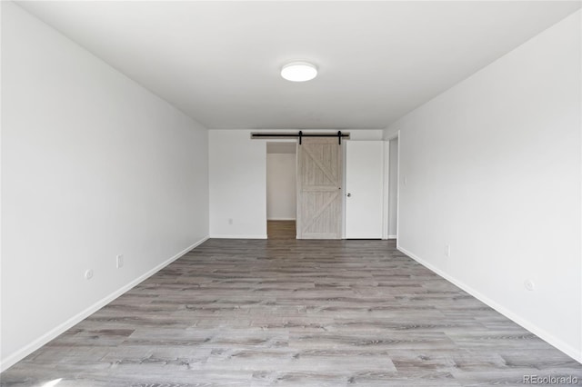 9451 W Hialeah Pl, Littleton, CO 80123 - unfurnished bedroom with wood finished floors, a barn door, and baseboards