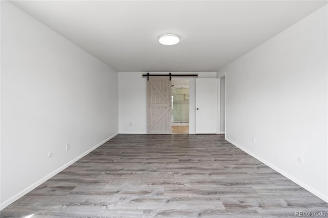 9451 W Hialeah Pl, Littleton, CO 80123 - unfurnished room with wood finished floors, a barn door, and baseboards
