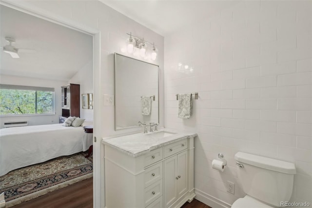705 S Alton Way Unit 4D, Denver, CO 80247 - bathroom featuring vanity, wood finished floors, ensuite bath, toilet, and tile walls