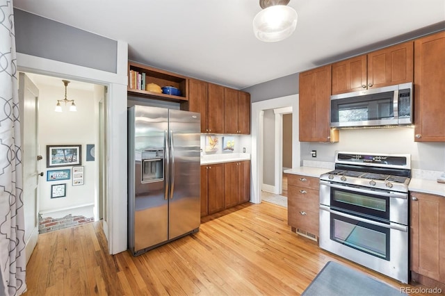 3044 W 40th Ave, Denver, CO 80211 - kitchen with stainless steel appliances, brown cabinets, light wood-style flooring, and light countertops