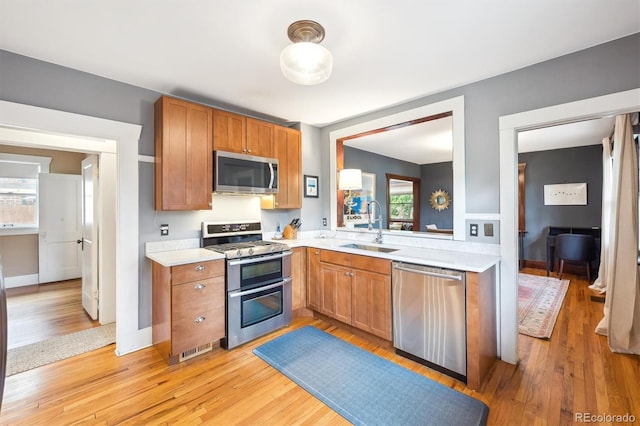 3044 W 40th Ave, Denver, CO 80211 - kitchen featuring stainless steel appliances, light countertops, light wood-style floors, and brown cabinetry
