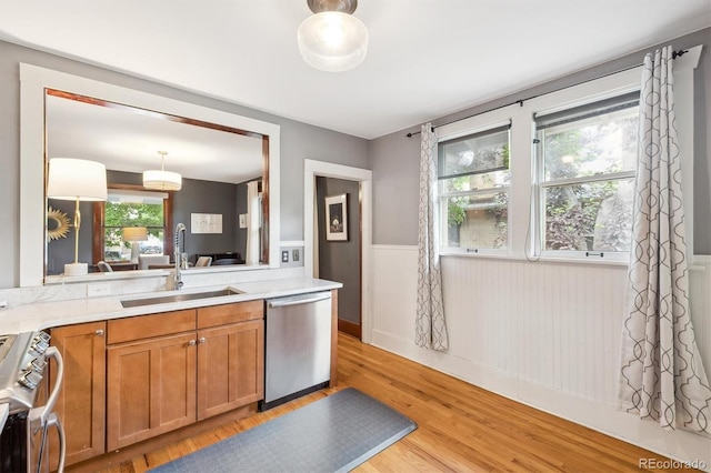 3044 W 40th Ave, Denver, CO 80211 - kitchen with stainless steel appliances, wainscoting, light wood finished floors, brown cabinetry, and light countertops