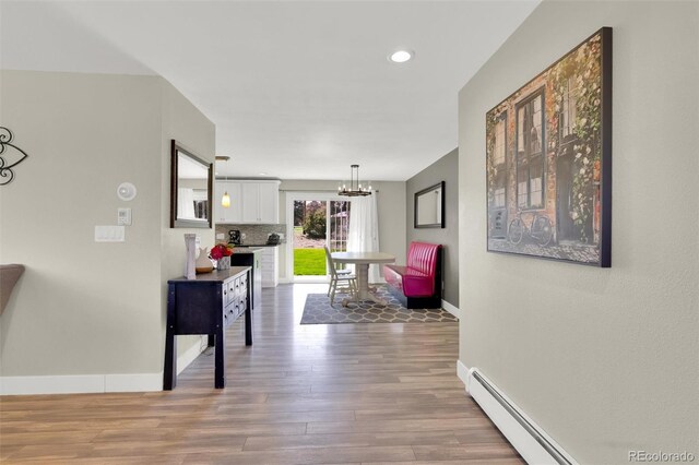 hall featuring wood finished floors, a chandelier, baseboards, a baseboard heating unit, and recessed lighting