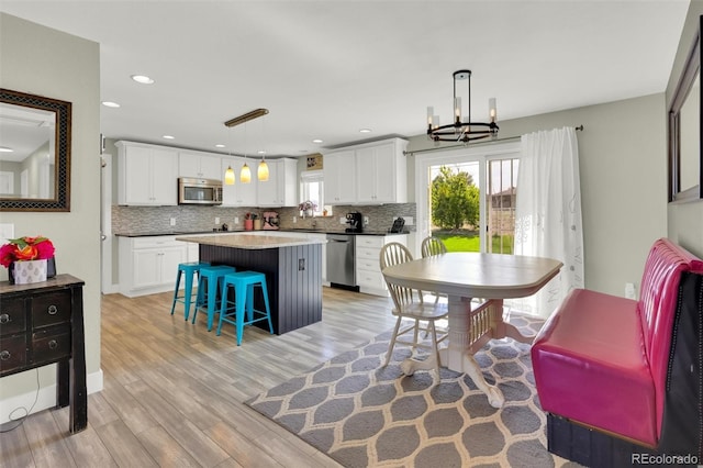 kitchen featuring appliances with stainless steel finishes, decorative backsplash, a kitchen breakfast bar, a kitchen island, and light wood-style floors
