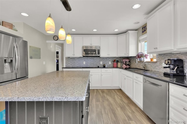 kitchen featuring appliances with stainless steel finishes, a sink, light wood-style flooring, tasteful backsplash, and recessed lighting