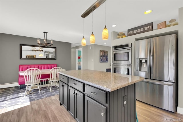 kitchen featuring stainless steel appliances, light wood-type flooring, hanging light fixtures, a center island, and recessed lighting