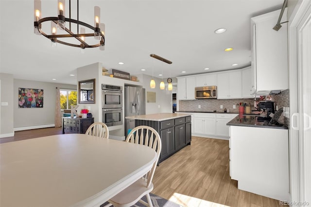 kitchen featuring appliances with stainless steel finishes, light wood-style floors, white cabinetry, a chandelier, and a center island