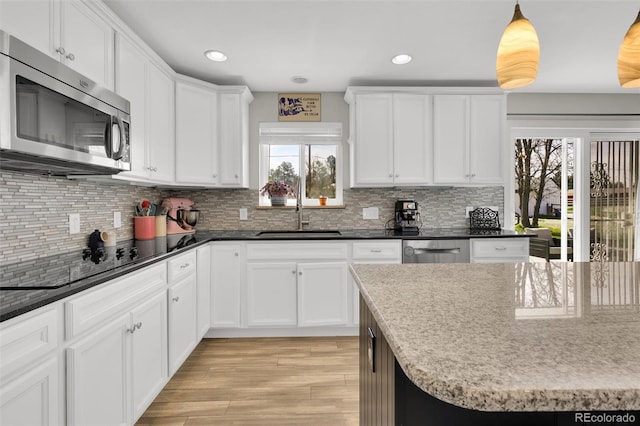 kitchen with appliances with stainless steel finishes, a sink, light wood-style floors, white cabinets, and recessed lighting