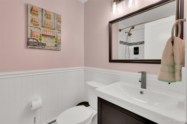 bathroom featuring wainscoting, toilet, vanity, and a shower
