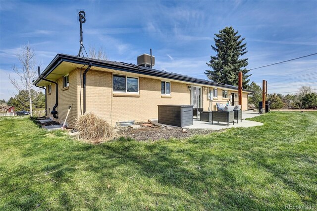 back of house with brick siding, a patio area, a yard, and outdoor lounge area