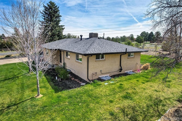 view of property exterior featuring a lawn, brick siding, and a shingled roof