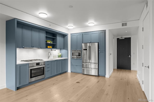 1750 Wewatta St Unit 1227, Denver, CO 80202 - kitchen with appliances with stainless steel finishes, open shelves, blue cabinets, tasteful backsplash, and light wood-style flooring