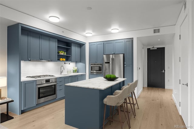 1750 Wewatta St Unit 1227, Denver, CO 80202 - kitchen featuring stainless steel appliances, blue cabinetry, open shelves, a kitchen bar, and decorative backsplash