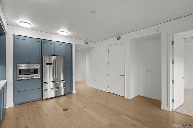 1750 Wewatta St Unit 1227, Denver, CO 80202 - kitchen featuring stainless steel appliances, blue cabinets, light wood finished floors, and light countertops