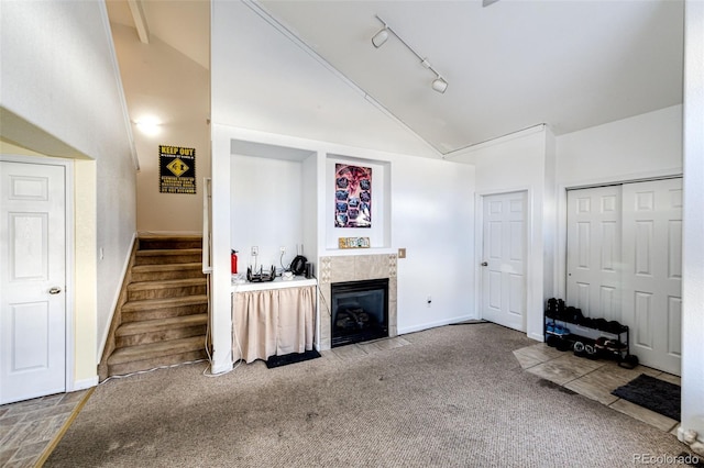 living room featuring high vaulted ceiling, carpet floors, rail lighting, and a tile fireplace