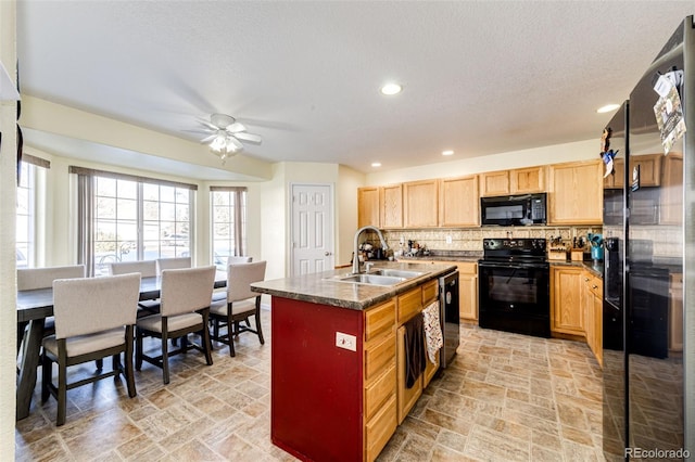 kitchen with ceiling fan, sink, tasteful backsplash, an island with sink, and black appliances