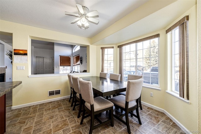 dining area featuring a fireplace, plenty of natural light, and ceiling fan