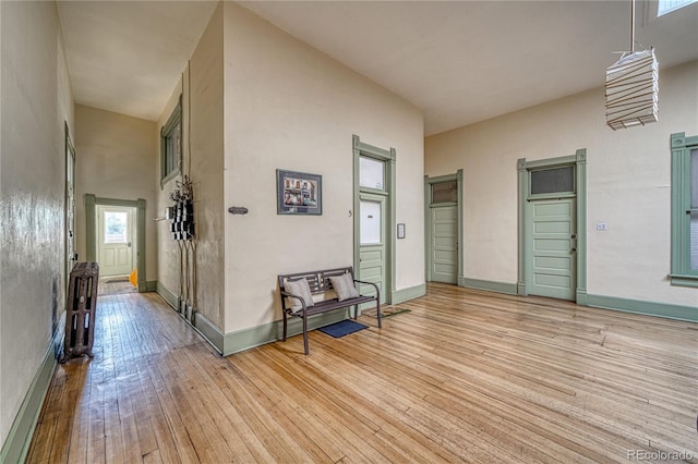 corridor with light hardwood / wood-style floors and a towering ceiling